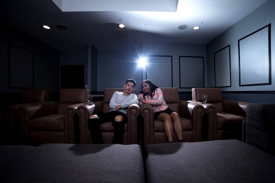 a couple sits in plush home cinema seating eating popcorn