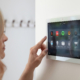 Woman Interacting With A Smart Home Tablet Base On Wall
